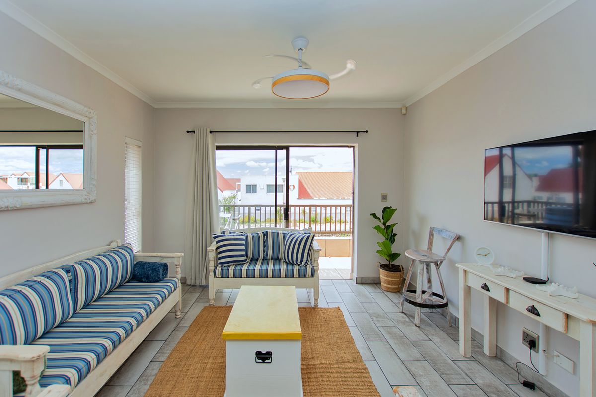 Bright living room featuring tiled flooring, a ceiling fan, and sliding glass doors that open onto a private balcony.