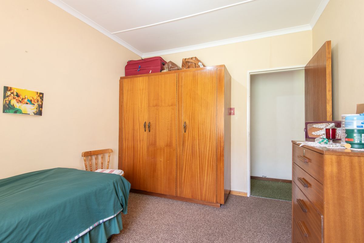 A bedroom featuring carpeted flooring and a built-in wooden wardrobe, providing functional storage space within the room.
