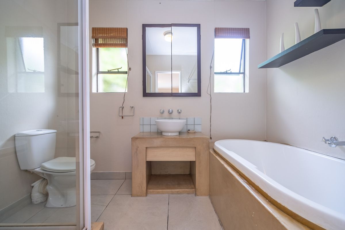A functional bathroom featuring a vessel sink vanity, a built-in bathtub, a separate toilet, and dual windows providing natural light.