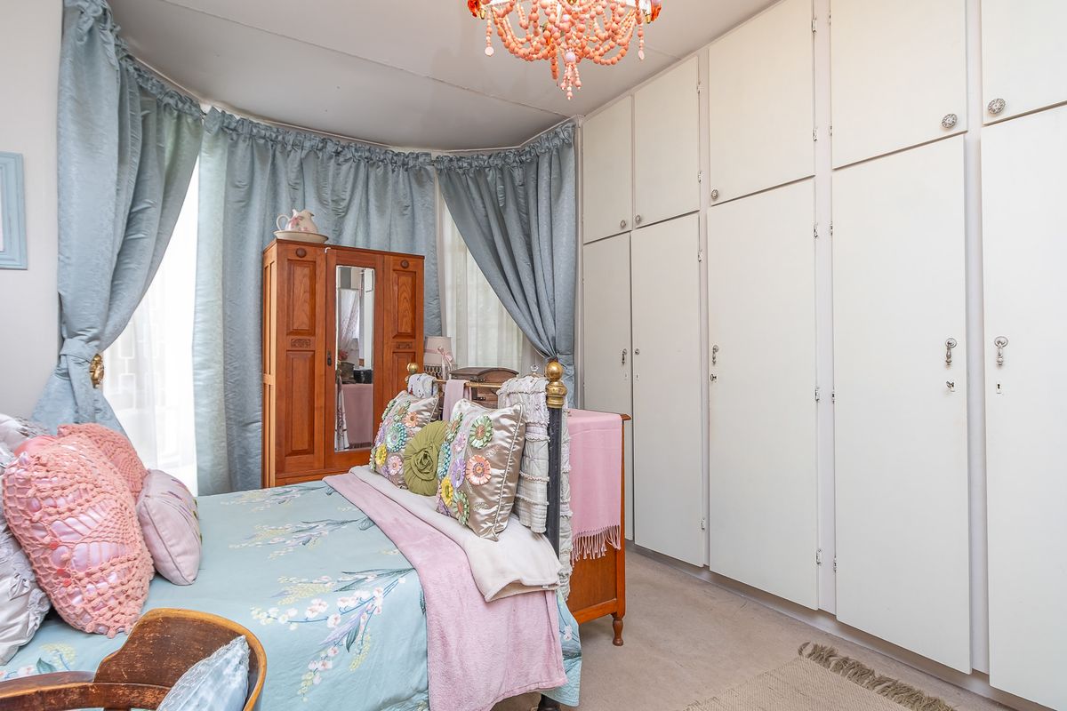 A bedroom featuring extensive floor-to-ceiling built-in cabinetry and a large bay window with curtains.