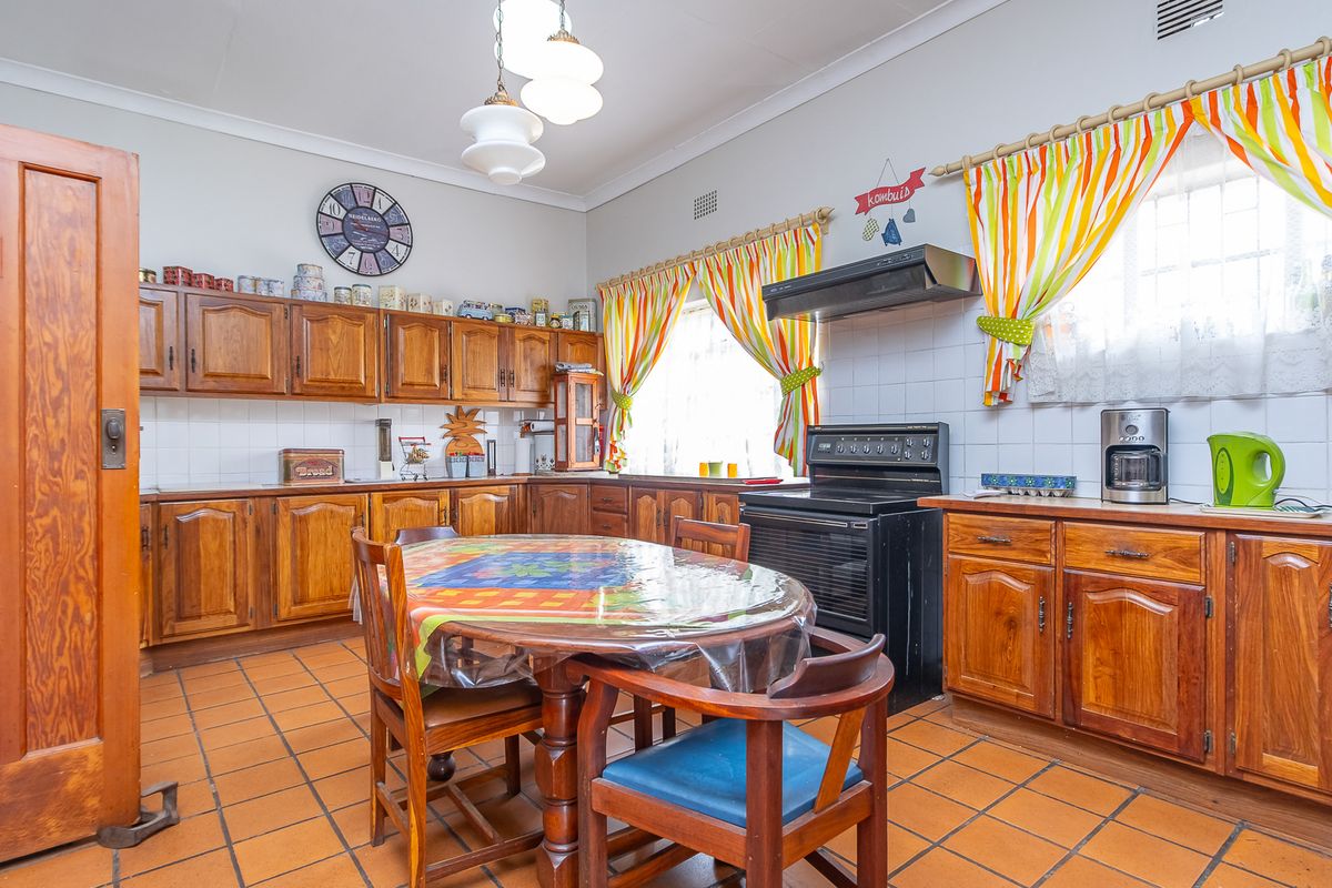 A traditional kitchen featuring wooden cabinetry, tiled flooring, and a built-in extractor fan, offering a functional layout with ample storage space.