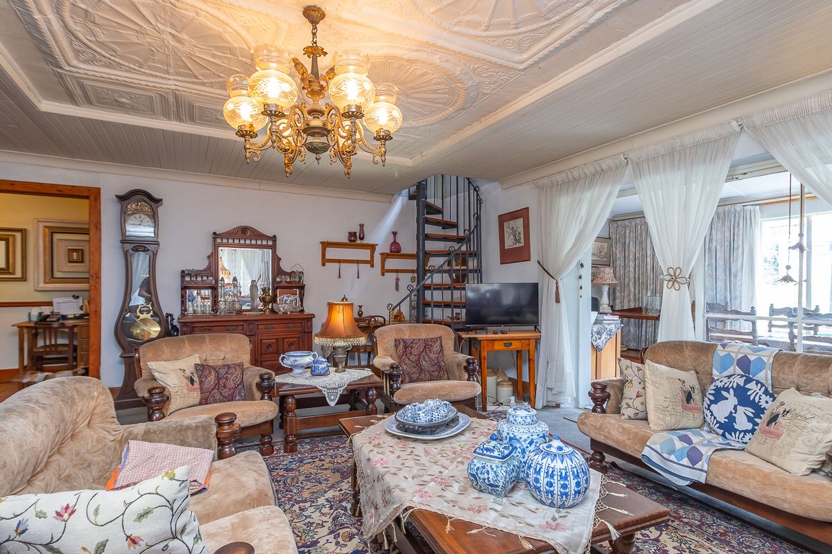 Spacious living room featuring a decorative pressed metal ceiling, ornate chandelier, and a spiral staircase leading to the upper level.