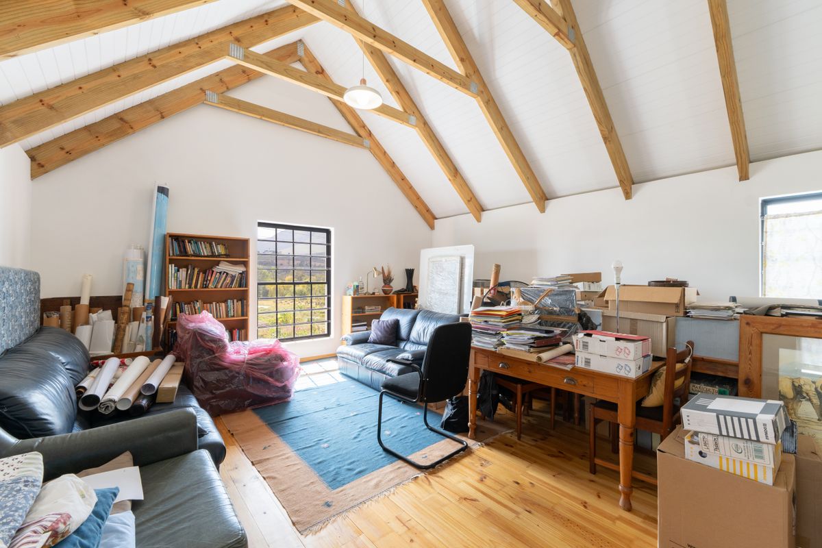 Spacious living area featuring high vaulted ceilings with exposed timber trusses, timber flooring, and large windows providing natural light and scenic views.