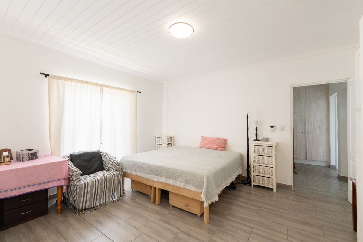 A bright bedroom featuring wood-look tile flooring, a tongue-and-groove ceiling, and an adjoining walk-in closet area.