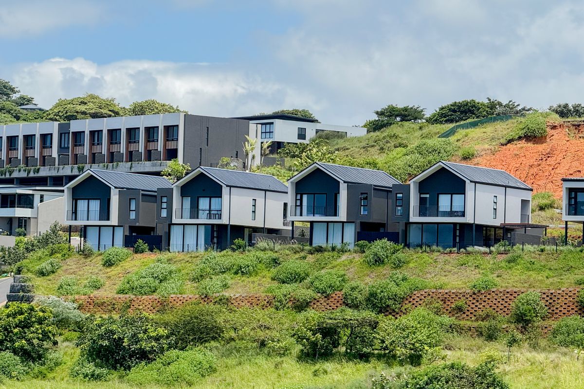 An elevated view of a modern townhouse complex featuring contemporary architectural design with pitched roofs and large glass sliding doors.