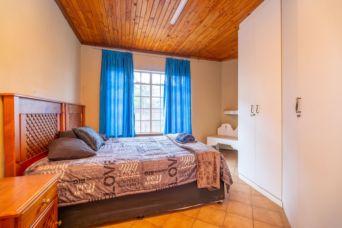 A bedroom featuring a timber-clad ceiling, built-in white cabinetry, and tiled flooring, providing a functional living space.
