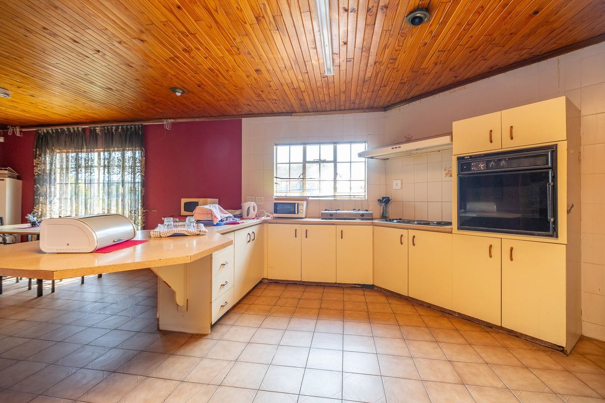 A dated kitchen featuring wood panel ceilings, tiled flooring, built-in oven, and a breakfast bar counter with ample cabinetry.