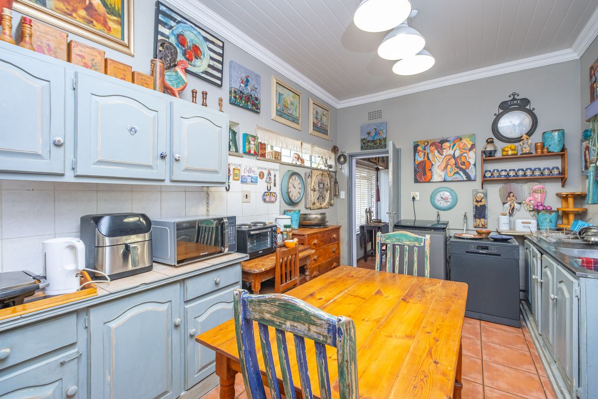A functional kitchen featuring painted cabinetry, tiled flooring, and a dedicated dining area, offering a traditional and lived-in aesthetic.