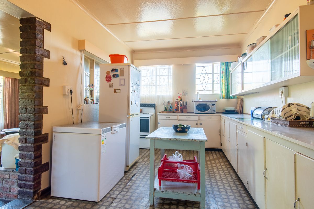 A dated kitchen featuring original cabinetry, tiled flooring, and a functional layout with built-in stove and ample counter space.