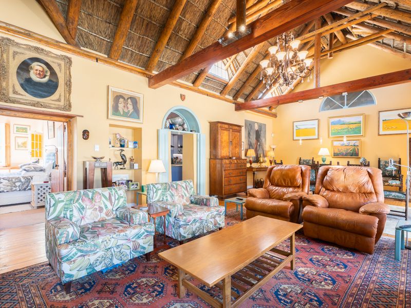 Spacious living room featuring a high vaulted thatched ceiling with exposed timber beams, hardwood flooring, and an elegant arched doorway.
