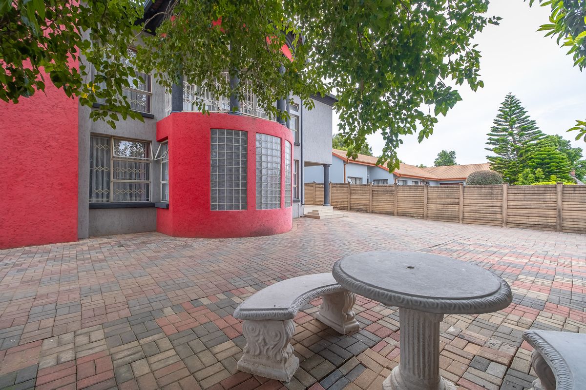 Rear exterior view of the property featuring a paved courtyard, glass block architectural detail, and perimeter boundary walling.