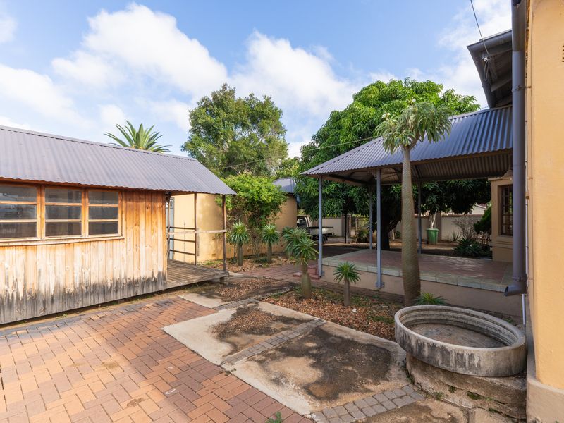 Outdoor courtyard area featuring a timber-clad outbuilding, a covered patio structure, and paved surfaces, providing functional exterior space for the office property.