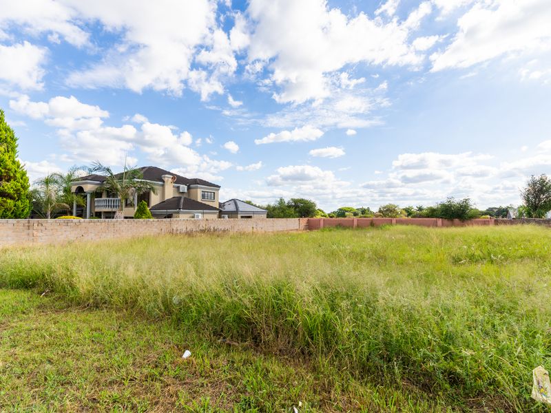A vacant residential plot featuring perimeter walling and established grass, offering a clear space for future development in a suburban setting.