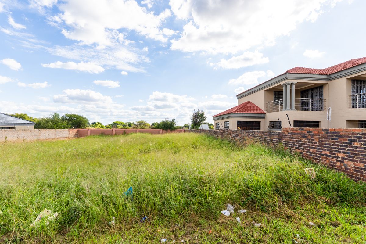 A vacant residential plot featuring perimeter brick walling and adjacent established housing, offering a blank canvas for future development.