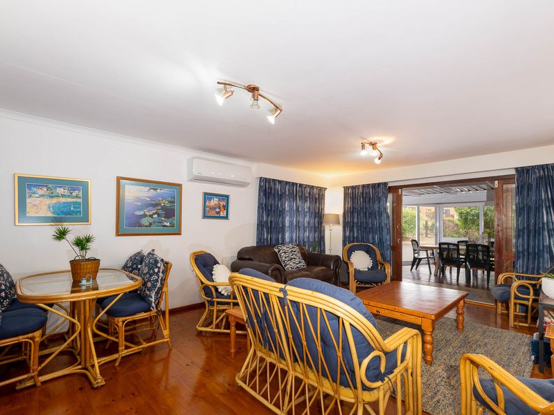 Spacious living room featuring polished hardwood flooring, a wall-mounted air conditioning unit, and large sliding glass doors providing access to the outdoor patio area.