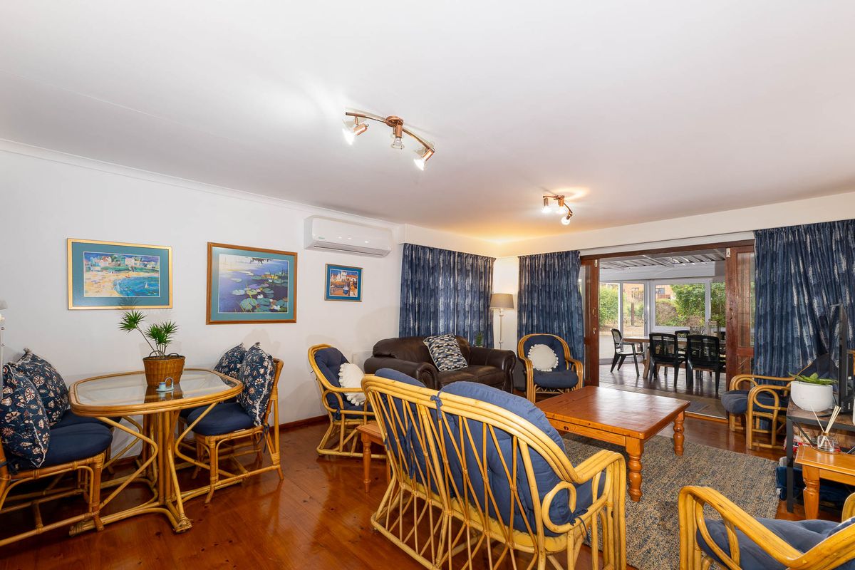 Spacious living room featuring polished hardwood flooring, a wall-mounted air conditioning unit, and large sliding glass doors providing access to the outdoor patio area.