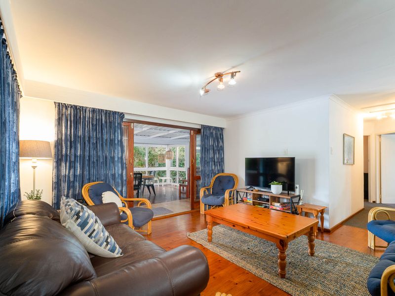 A comfortable living room featuring polished timber flooring and large sliding glass doors that provide direct access to an outdoor patio area.