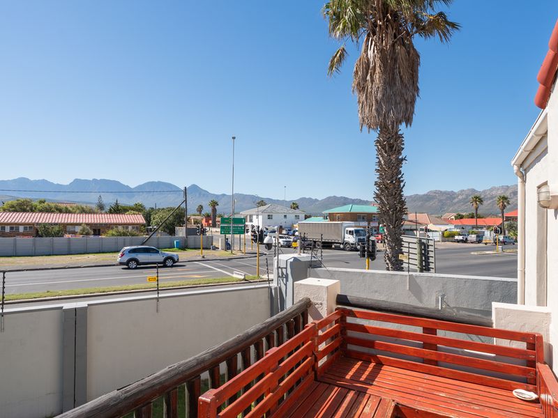 An elevated balcony featuring a timber balustrade and electric fencing, offering views of the surrounding street and mountain landscape.