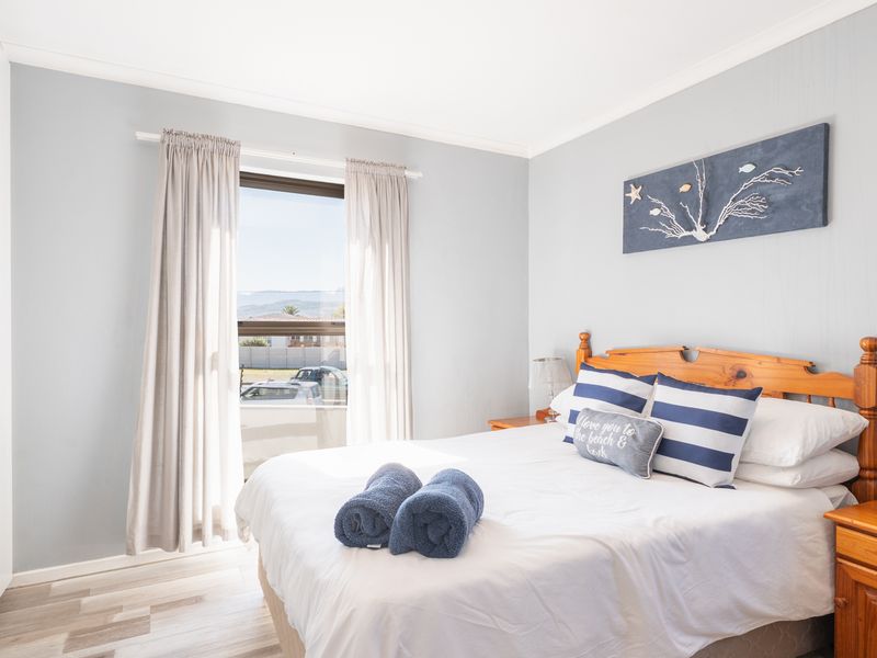 A bright and well-maintained bedroom featuring laminate flooring, a built-in wardrobe, and a window with natural light.