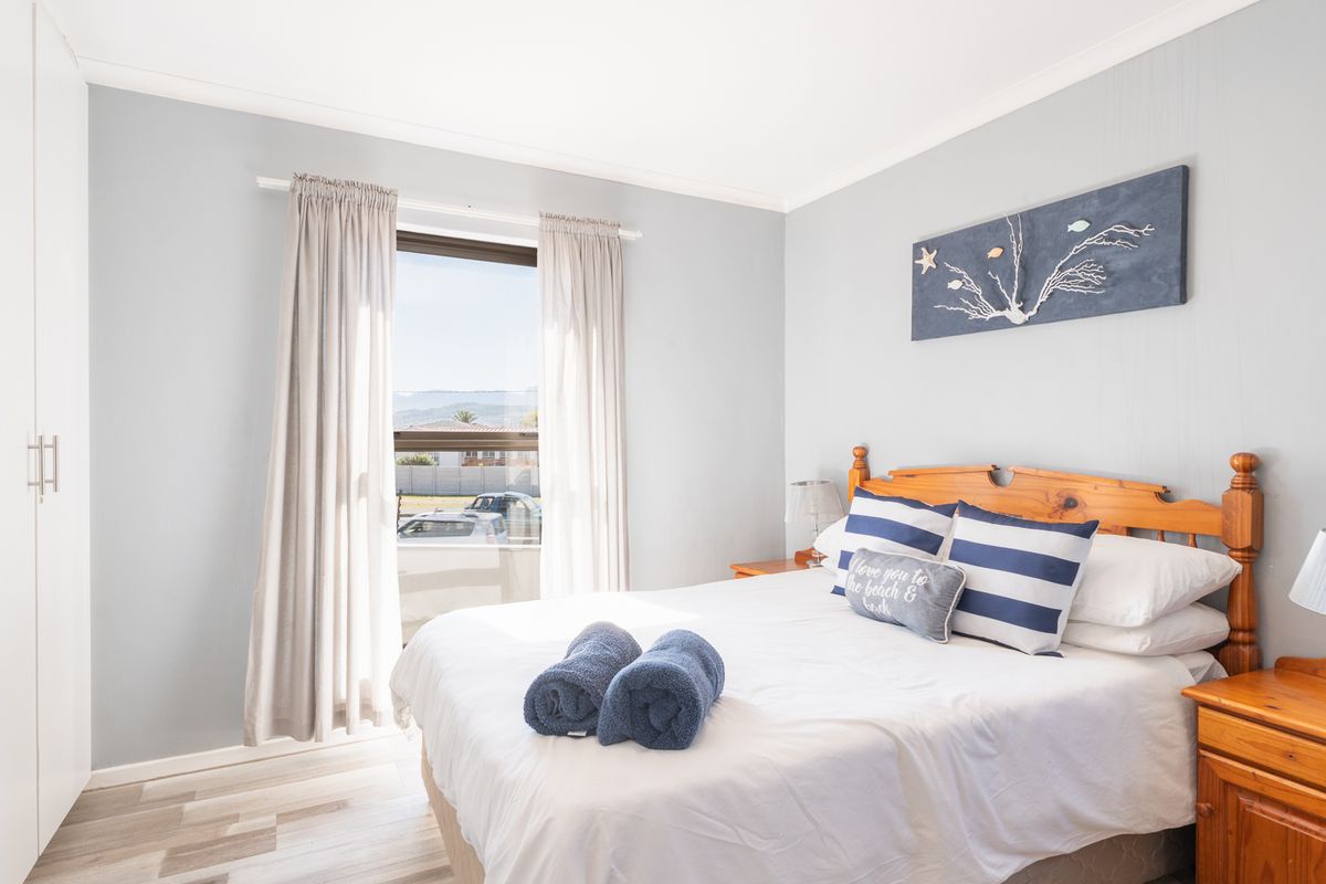 A bright and well-maintained bedroom featuring laminate flooring, a built-in wardrobe, and a window with natural light.