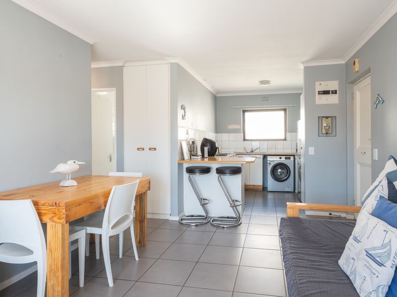 Open-plan living and kitchen area featuring tiled flooring, a breakfast counter, and built-in cabinetry, providing a functional and connected living space.