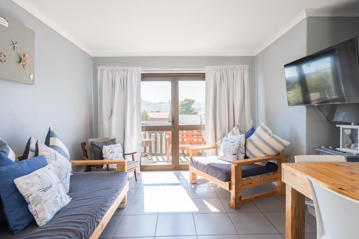 A bright living room featuring tiled flooring, neutral wall finishes, and a sliding glass door providing access to an outdoor balcony area.