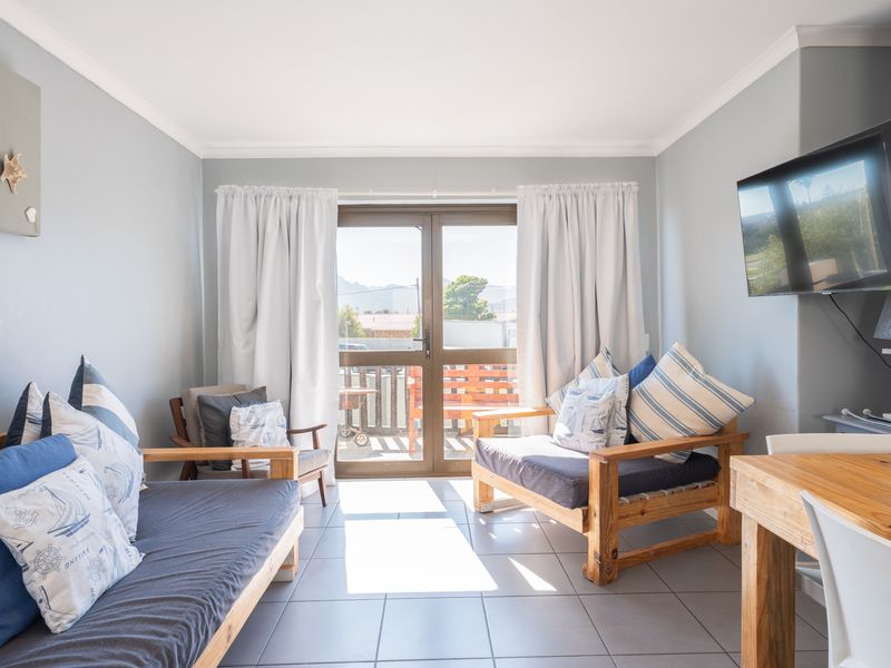 A bright living room featuring tiled flooring, neutral wall finishes, and a sliding glass door providing access to an outdoor balcony area.