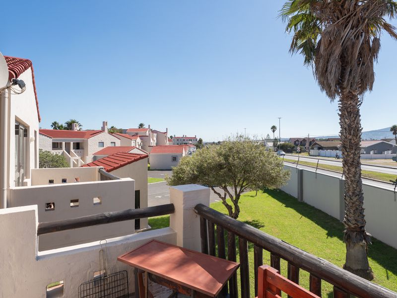 A balcony overlooking the complex grounds and surrounding neighbourhood, featuring timber railings and views of the nearby mountain range.