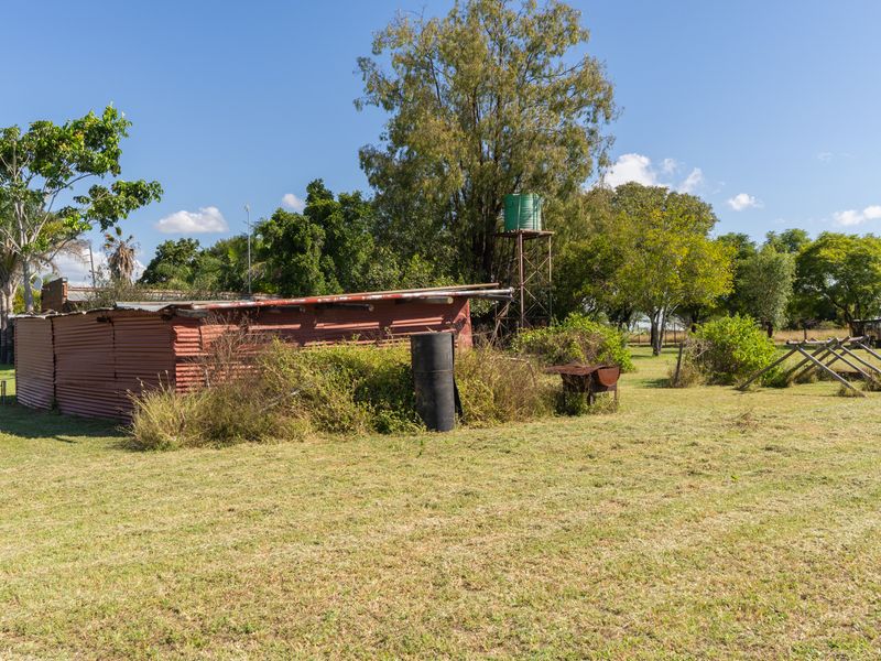 A view of a rustic corrugated iron shed on the farm property, featuring an elevated water tank and surrounding open land.