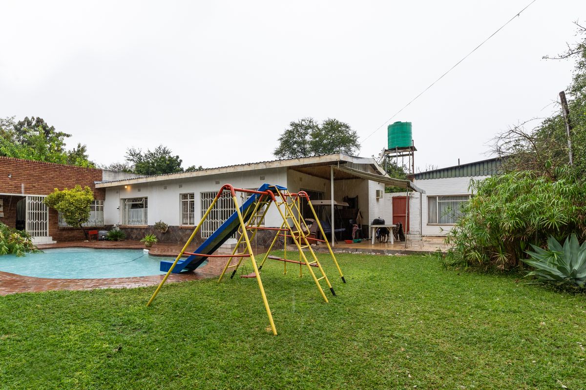Rear view of the farm property featuring a swimming pool, covered patio area, and a water storage tank on a raised stand.