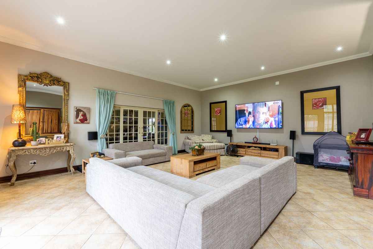 Spacious living room featuring tiled flooring, recessed downlighting, and double glass doors leading to the exterior.