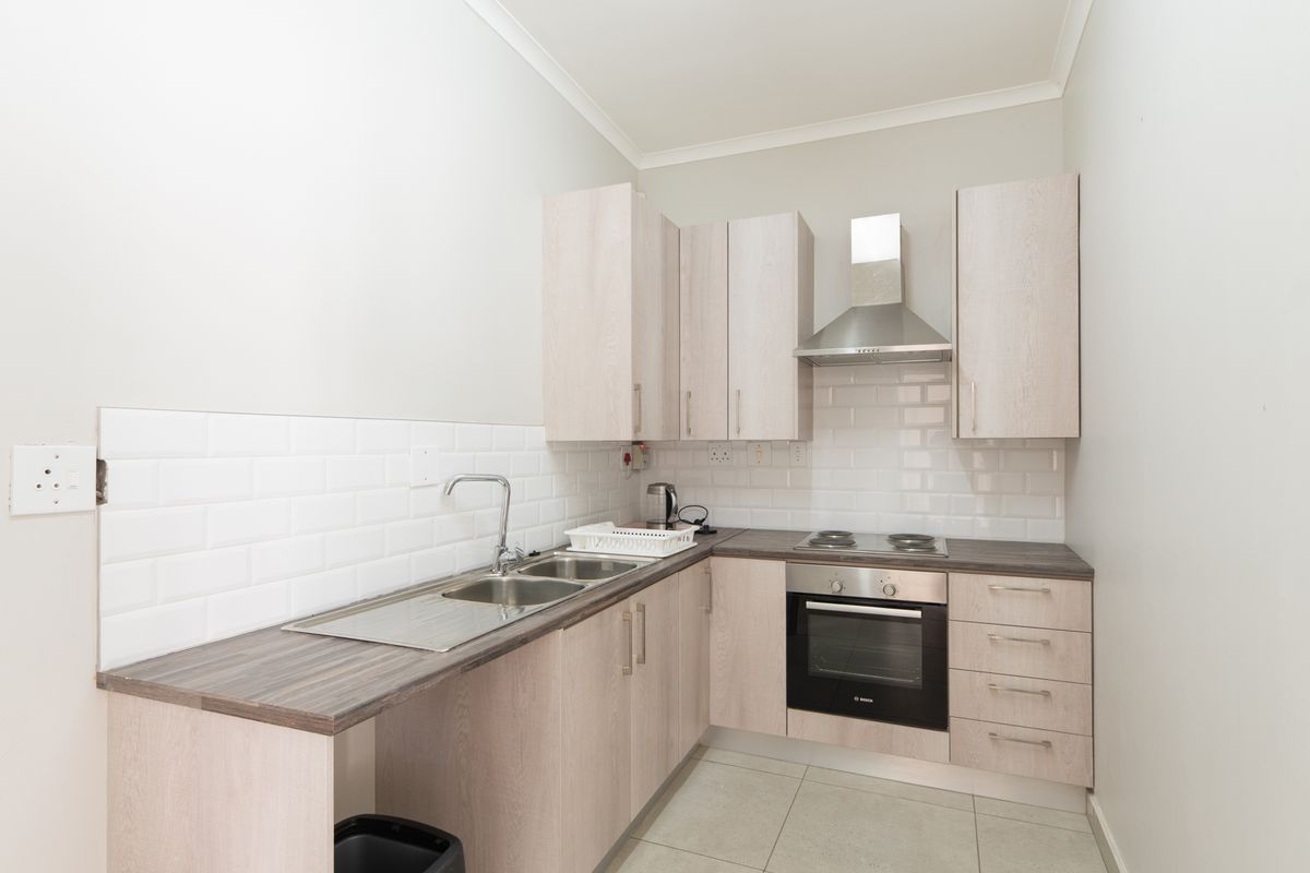 Compact kitchen featuring light wood-tone cabinetry, subway tile backsplash, stainless steel appliances, and durable laminate countertops.
