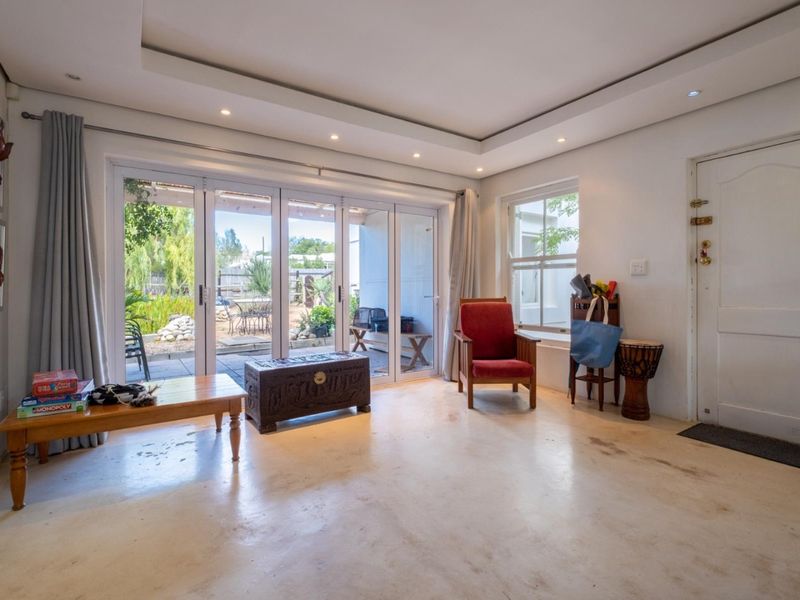 Bright living room featuring a coffered ceiling with recessed lighting, tiled floors, and large sliding glass doors providing direct access to the rear patio.