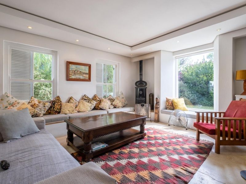 Bright and inviting living room featuring a built-in window seat, cast iron fireplace, recessed ceiling lighting, and large windows with plantation shutters.