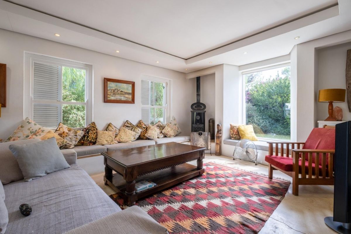 Bright and inviting living room featuring a built-in window seat, cast iron fireplace, recessed ceiling lighting, and large windows with plantation shutters.