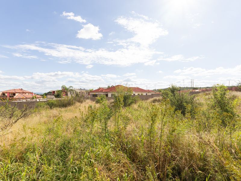A view of a vacant residential plot featuring natural vegetation and surrounding neighborhood housing.