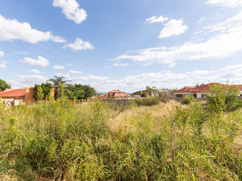 A vacant residential plot featuring overgrown natural vegetation, situated within an established neighborhood with surrounding residential properties.