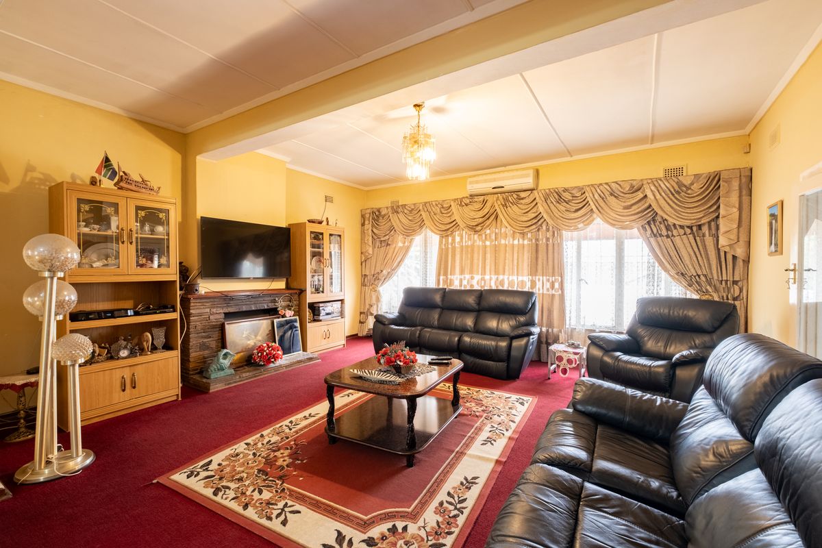 Spacious living room featuring a brick fireplace, split-system air conditioning, and carpeted flooring, offering a traditional layout with ample natural light.