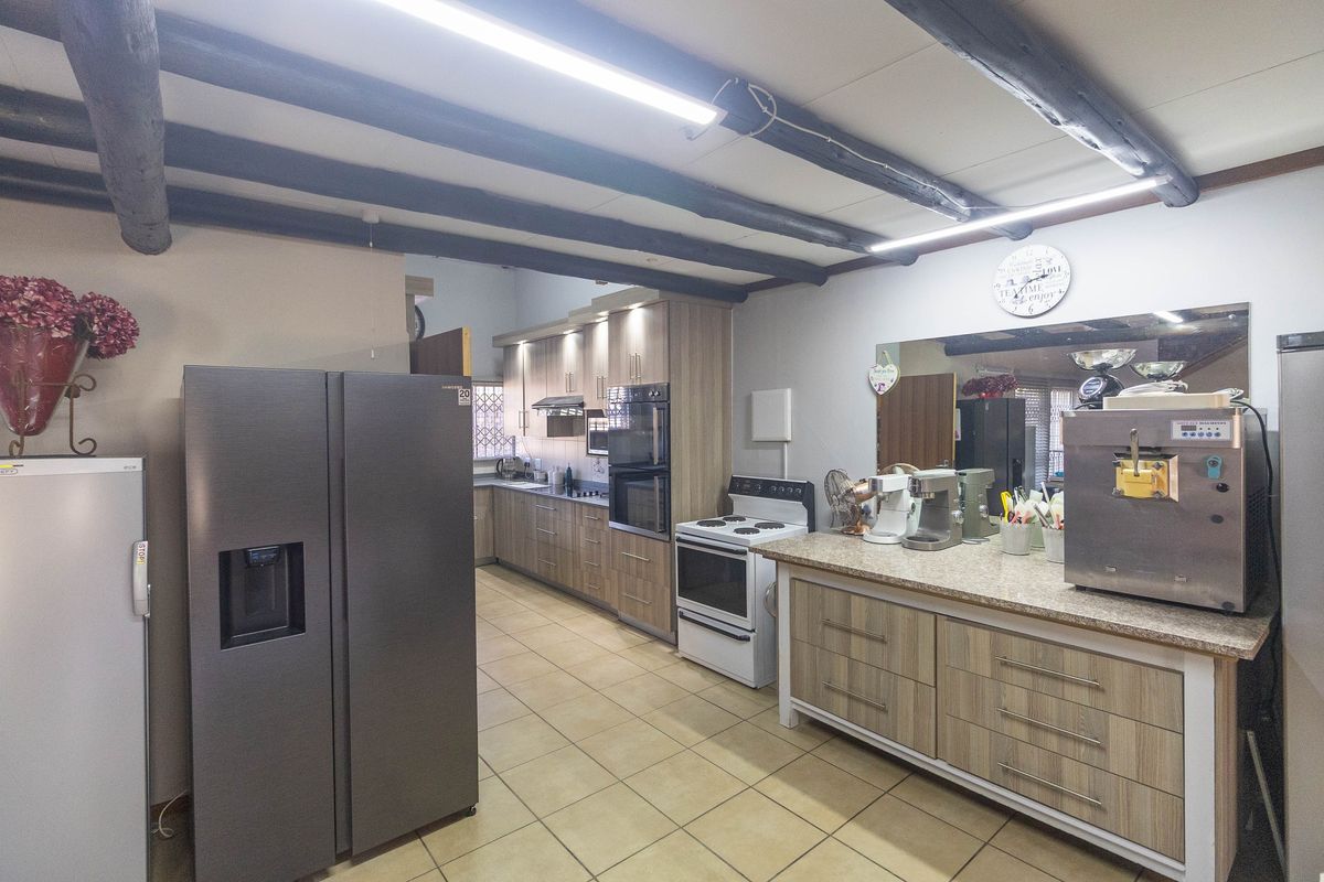 Spacious kitchen featuring wood-look cabinetry, granite countertops, built-in oven, and exposed ceiling beams, offering ample storage and workspace.