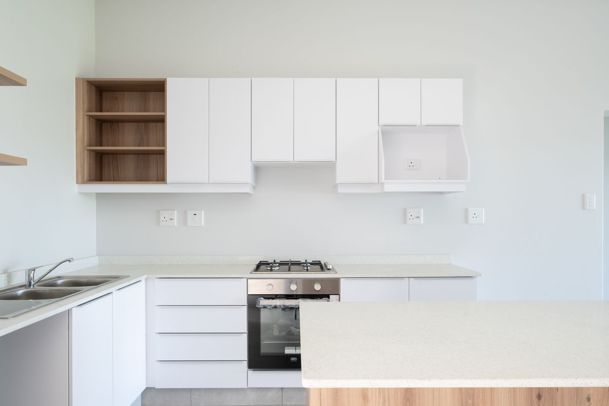 Modern kitchen featuring white cabinetry, stone countertops, a built-in gas hob, and an integrated oven, offering a clean and functional workspace.