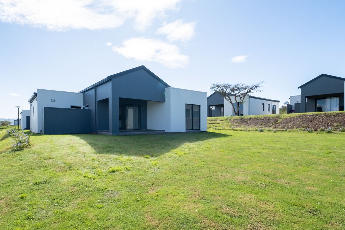 A view of the rear exterior of a modern residential property featuring clean lines, neutral tones, and a well-maintained lawn.