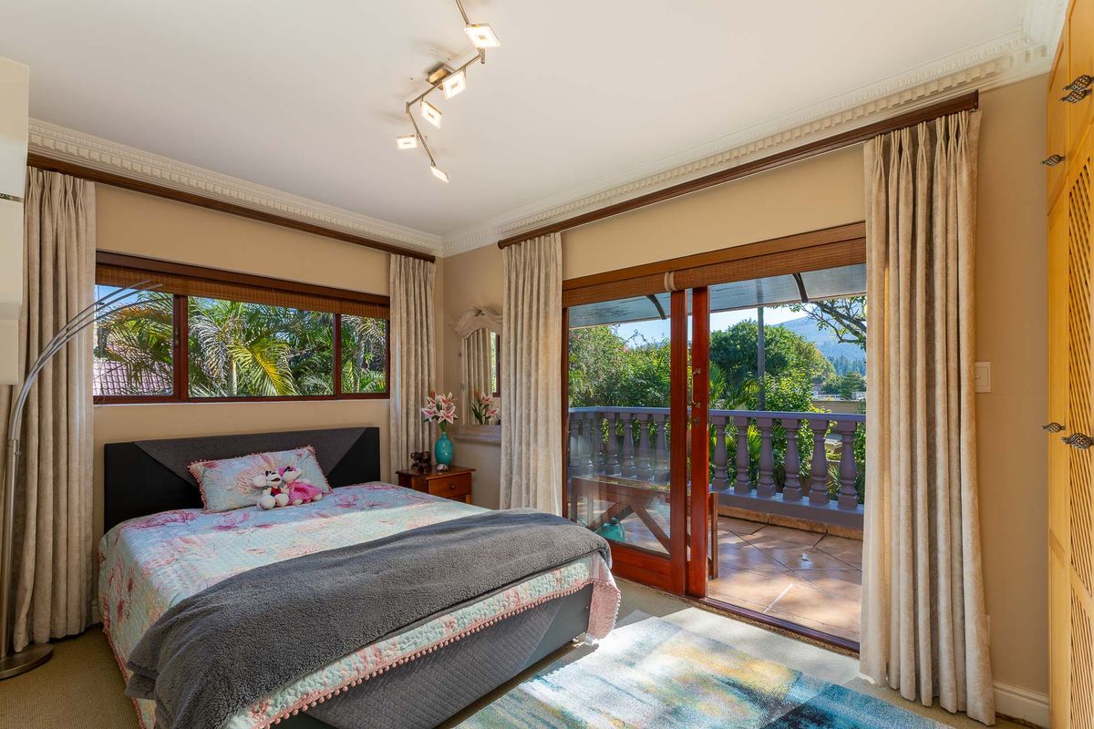 Spacious bedroom featuring large windows, built-in wardrobes, and sliding glass doors that open onto a private balcony with scenic views.