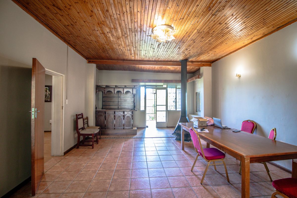 Spacious living area featuring a timber-clad ceiling, tiled flooring, and a built-in fireplace, offering direct access to the outdoor area.