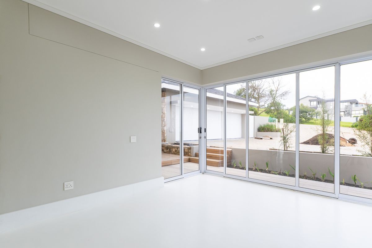 Bright, modern living area featuring expansive floor-to-ceiling sliding glass doors that provide seamless access to the outdoor patio and garden.