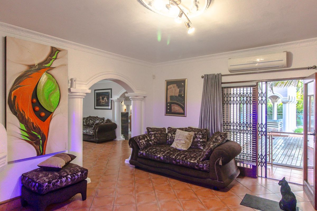 Spacious living area featuring terracotta floor tiles, decorative archways with columns, and direct access to an outdoor patio through a security gate.