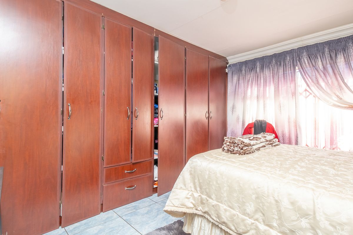 A bedroom featuring extensive floor-to-ceiling built-in wooden cabinetry and tiled flooring, providing ample storage space.