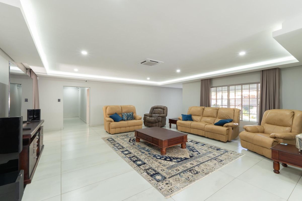 Spacious living room featuring recessed ceiling lighting, large format floor tiles, and a ducted air conditioning unit.