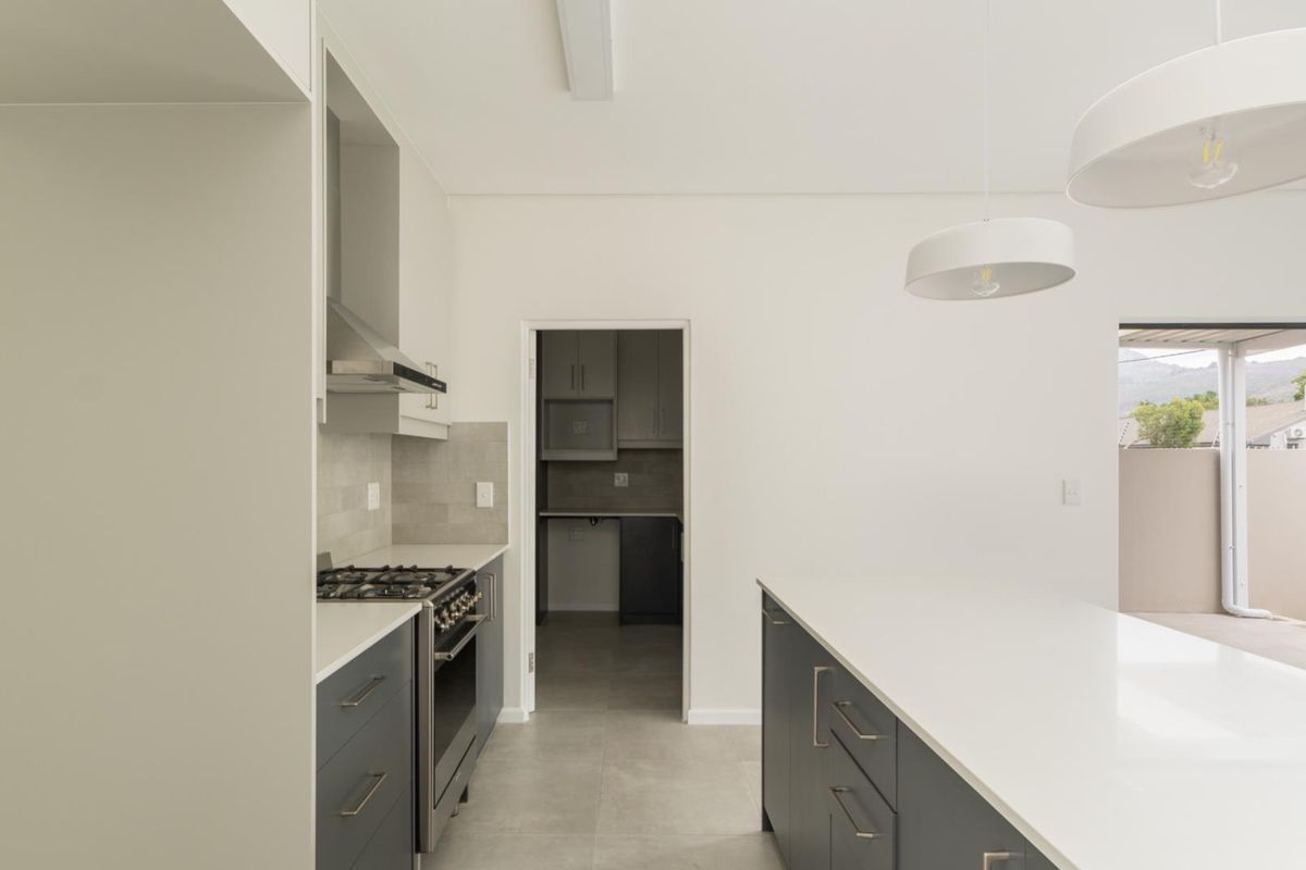 Modern kitchen featuring a central island, gas cooktop, stainless steel extractor fan, and a convenient adjoining scullery area with neutral finishes.