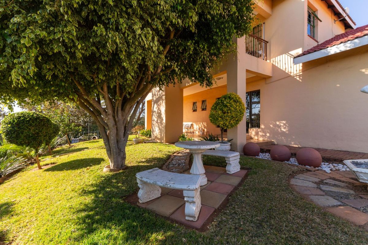 A well-maintained rear garden area featuring a covered patio, paved seating space, and established landscaping adjacent to the main dwelling.