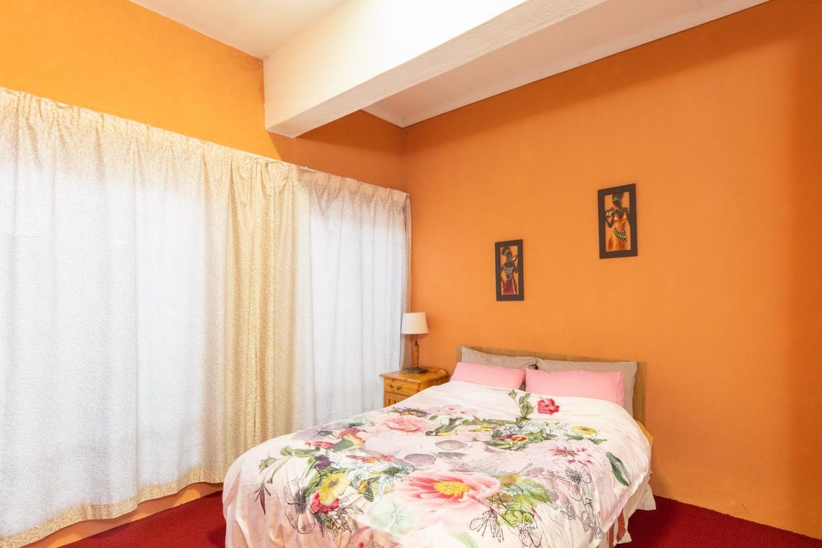 A bedroom featuring orange walls, carpeted flooring, and built-in cabinetry, offering a functional space with potential for modern updates.